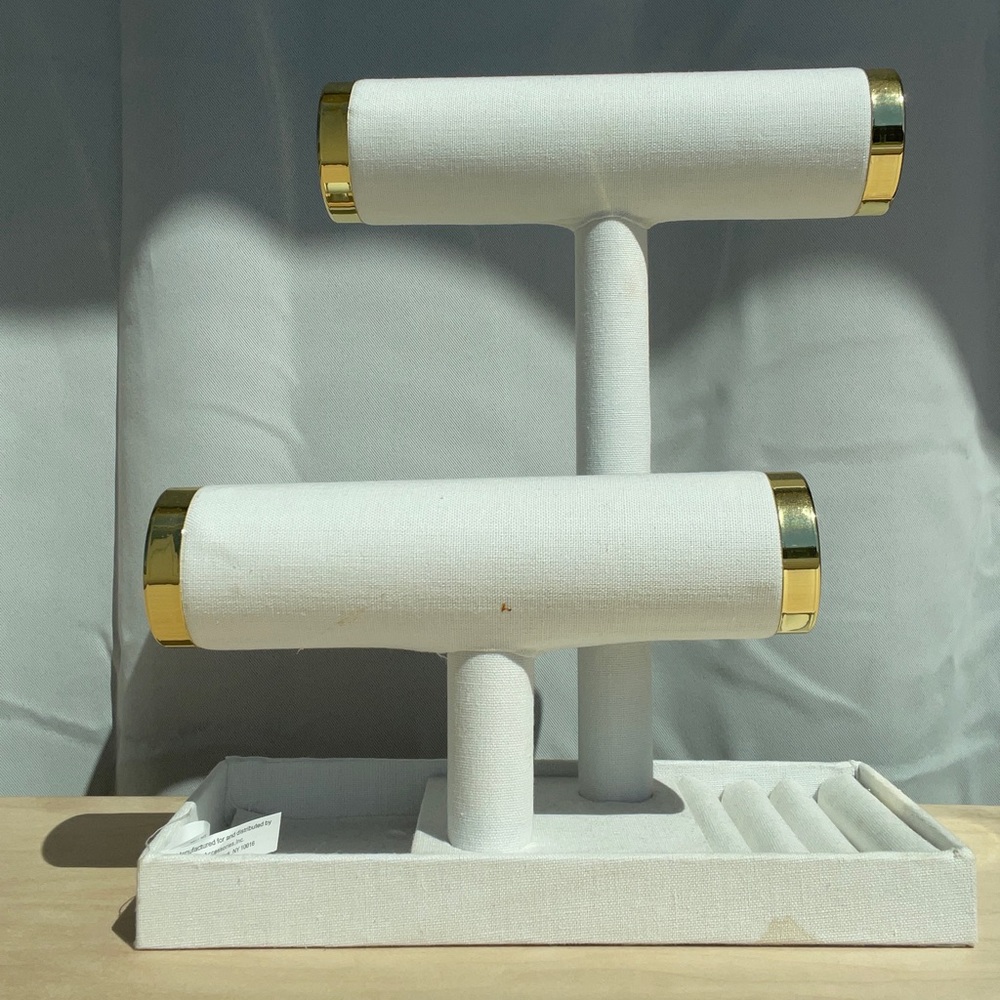 White jewelry stand with gold detailing.